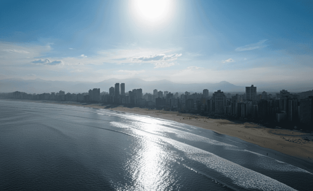 Vista aérea da Praia da Enseada, no Guarujá (SP), no litoral paulista, com faixa de areia extensa, prédios à beira-mar e condições do mar e do tempo típicas da região costeira
